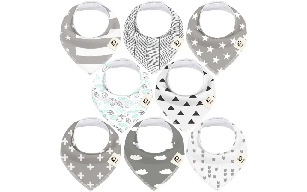 Selection includes grey star-stripes, herringbone weave, minimalist white stars, aqua leaves, geometric triangles, white crosses, dreamy grey clouds, and modern arrows. These highly absorbent 100% cotton bibs are purely handcrafted and guaranteed to pass international GOTS and OEKO-TEX certifications through our OEM, ODM, and Customized services.