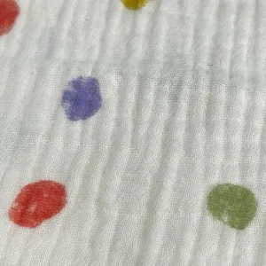 Premium infant-grade muslin fabric featuring vibrant multi-colored reactive dye spots. Advanced color fastness ensures fade-resistant, durable prints. Professional OEM/ODM manufacturing from Chinese B2B baby textile factory for quality bibs for baby.