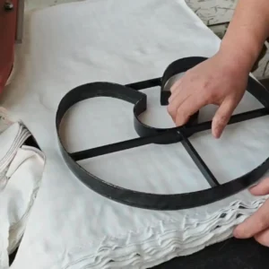 Precision Die-Cutting Process preparation for next batch involves strategic metal die repositioning on fresh fabric layers. Professional positioning ensures production continuity. OEM/ODM manufacturing from professional Chinese B2B baby textile factory.