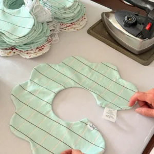 Precise Stitching and Finishing Process completion reveals perfect bibs for baby featuring flawless flatness, professional appearance, and premium quality. Precision ironing creates refined product aesthetics. OEM/ODM manufacturing from professional Chinese B2B baby textile factory.