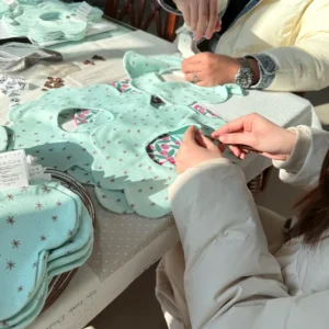 Snap Fastening Process includes professional manual snap installation for custom and specialty materials. Skilled technician application ensures targeted reinforcement. OEM/ODM manufacturing from professional Chinese B2B baby textile factory for specialty designs.