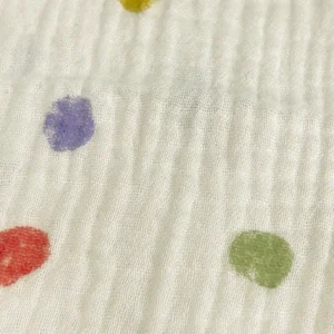 Macro view showcasing vibrant polka dots and fine muslin weave texture. High-definition print clarity and premium cotton construction. OEM/ODM specialist—Chinese textile factory for premium bibs for baby manufacturing.