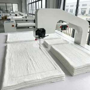 Our industrial vertical cutting machine slices through multiple layers of gauze fabric to separate different component panels cleanly. As a professional baby textile factory in China, we implement standardized shaping processes to guarantee that every independent section maintains uniform sizing before heading into subsequent sewing stages.