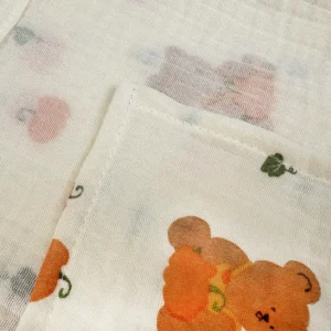 Macro close-up reveals charming bear and pumpkin characters with superior muslin weave quality. Precise print clarity demonstrates expert autumn-themed craftsmanship. Professional OEM/ODM services from Chinese B2B baby textile factory.