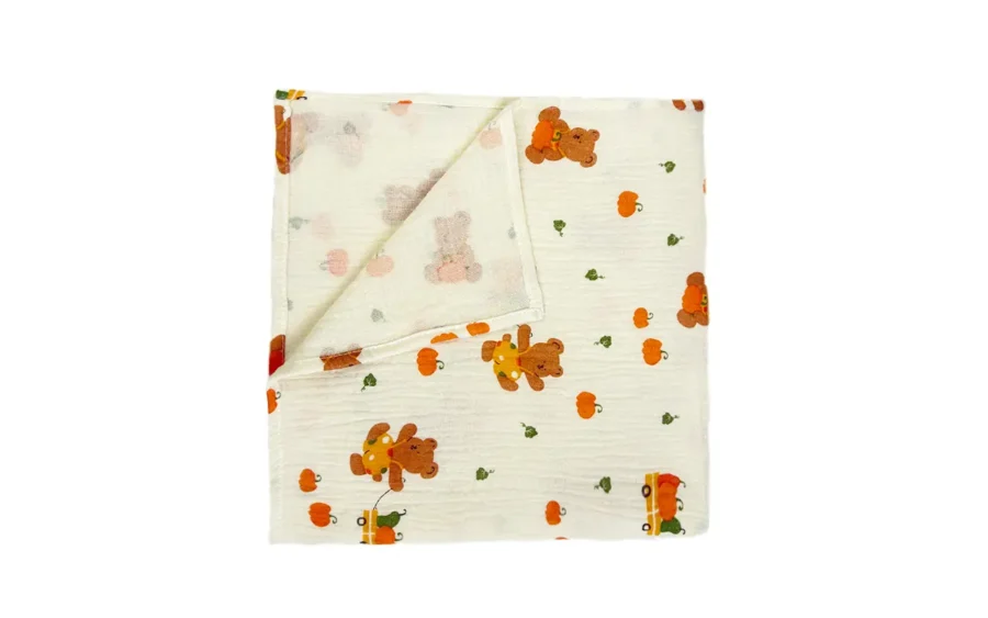 Neatly folded Harvest Joy muslin cotton blanket reveals complete size, premium fabric quality, and balanced bear and pumpkin print distribution. Versatile multi-use seasonal design. OEM/ODM wholesale from professional Chinese B2B textile factory.