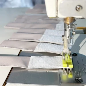 Our functional nylon straps are pre-fitted with heavy-duty Velcro patches using precise, straight-line industrial stitch paths. As a specialized baby textile factory in China, we run highly efficient component sub-assembly lines to ensure every fastening point meets extreme tensile strength standards.