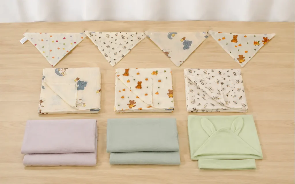 Muslin baby products multi-color complete display featuring printed bibs and solid-color blankets. 100% pure cotton material with breathable soft texture. We provide professional OEM customization supporting color selection, print design, and specification customization comprehensive services.