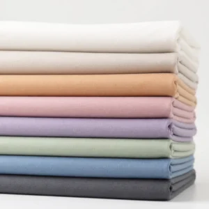 Our premium 100% cotton solid fabrics are neatly stacked to showcase a diverse range of market-ready pastel and neutral color options. As an established baby textile factory in China,