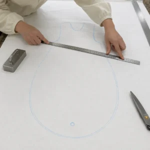 Our quality-focused pre-cutting calibration phase uses calibrated steel rulers to double-check the chalked margin lines on the spread fabric layers. As a compliance-focused baby textile factory in China, we execute this manual calibration routine to guarantee absolute alignment with international ergonomic metrics.