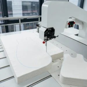 Our structural internal insulation padding undergoes mechanized cutting utilizing a vertical band knife machine to ensure clean, razor-sharp edge profiles across thick fiber layers. Operating as a precision-driven baby textile factory in China, we manage high-capacity bulk cutting to secure shape consistency right before final product assembly.
