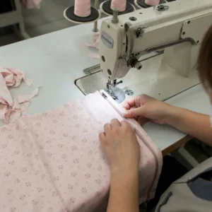 Our industrial sewing line utilizes high-precision flat-seam machinery to install smooth, center-opening zippers straight down the front panel of the garment. As an established baby textile factory in China, we maintain strict operator guidance to guarantee straight needle paths and waveless tape alignment.