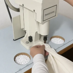 Our heavy-duty mechanical button-setting station uses dedicated molding presses to streamline the precise integration of premium snap fasteners into multi-layered textiles. Our baby textile factory in China enforces strict safety guidelines at every pressing unit to ensure maximum durability.