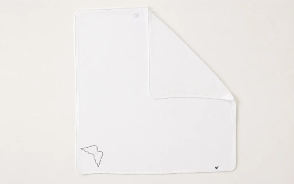 Our B2B custom cotton baby blanket features a soft 100% cotton knit, a white merrow edge, angel-wing applique, and logo label, made by our Hangzhou, China OEM/ODM factory with 40+ years of experience.