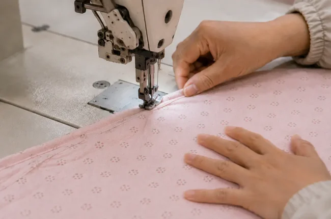 Our Cutting & Sewing process focuses on precision handling. Our industrial sewing machines ensure that every soft infant fabric layer is perfectly aligned, delivering highly durable construction for brand partners.